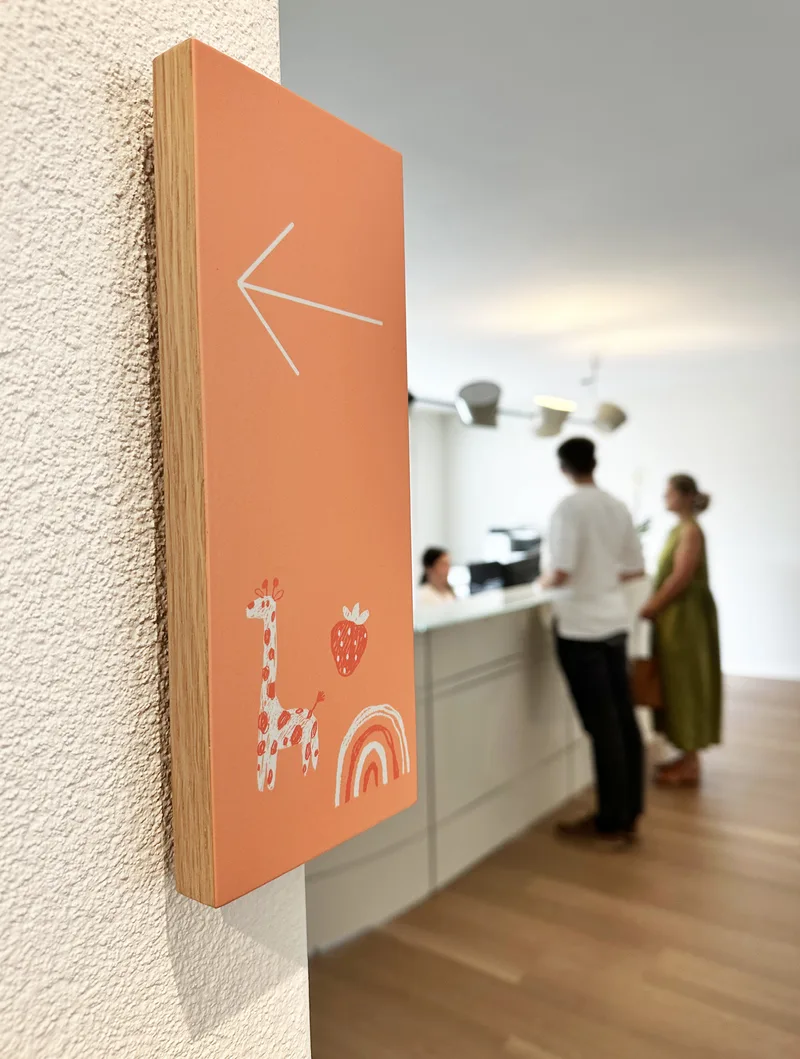 Cartello arancione con freccia accanto alla reception dello studio.